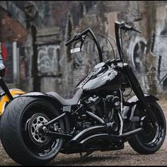 a black and silver motorcycle parked in front of a wall with graffiti painted on it