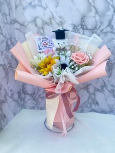 a bouquet of flowers in a vase with a graduation cap on the top and congratulations card attached to it