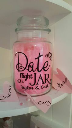 a jar filled with pink candles sitting on top of a white table next to a sign