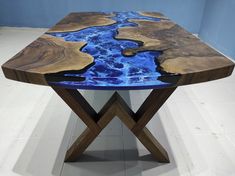 a wooden table with blue paint on it and a cross leg base in the middle