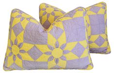 two purple and yellow decorative pillows sitting next to each other