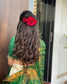 a woman with long dark hair wearing a green dress and red flower in her hair