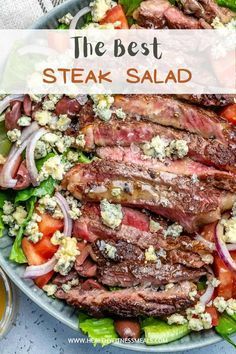 steak salad with tomatoes, lettuce and feta cheese on top in a bowl