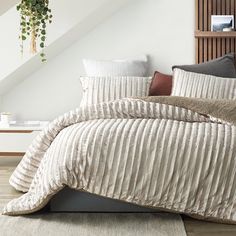 a bed that has some pillows on top of it and a plant in the corner