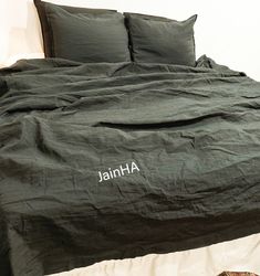 an unmade bed with two pillows on top of it and the name jahn written in white