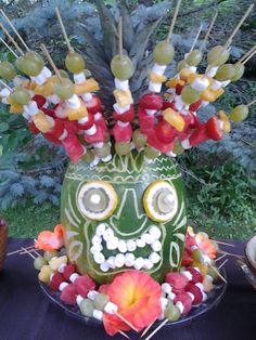 a green mask made out of fruit on a table next to a potted plant