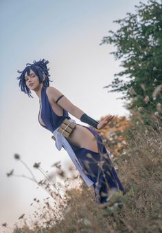 a woman with blue hair is standing in tall grass