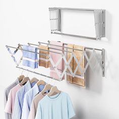 several shirts hanging on clothes racks in a white room