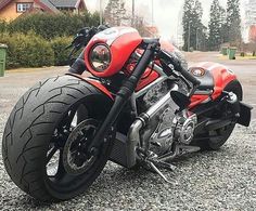 a red motorcycle parked on top of a gravel covered parking lot next to a house