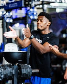 a man standing in front of a gym machine holding his hands out to the side