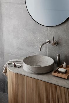 a bathroom sink sitting under a round mirror