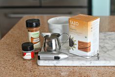 coffee, spices and salt sit on a marble counter top next to a box of tazo