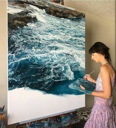 a woman standing in front of a large painting