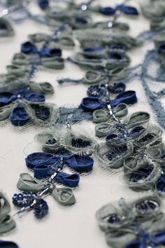 blue and grey fabric with flowers on it, including beads and sequins in the center