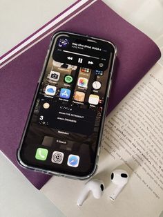 an iphone sitting on top of a book next to ear buds