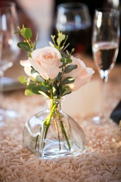 a vase filled with flowers sitting on top of a table next to two wine glasses