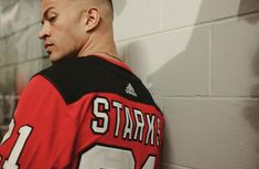 a man in a jersey leaning against a wall with his head turned to the side