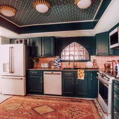 a kitchen with green cabinets and an area rug on the floor in front of the stove