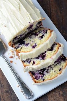 slices of blueberry bread on a white plate with a knife and fork next to it