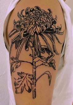 a woman with a tattoo on her arm holding onto a large dandelion flower