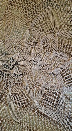 a crocheted doily is laying on a tablecloth that looks like it has been made from yarn