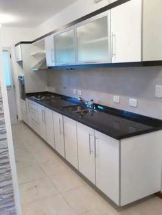 an empty kitchen with white cabinets and black counter tops on the counters is seen in this image