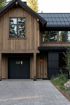 a large wooden house with two garage doors on the front and one door open to let in light