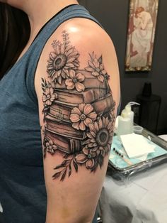 a woman's arm with books and flowers on it