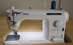 a white sewing machine sitting on top of a wooden table