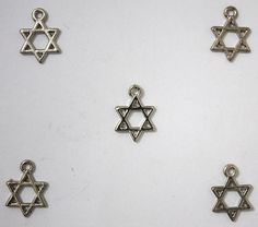 six silver colored charms with star of david in them on a white surface, one has a cross and the other is a star of david