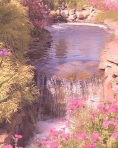 there is a small waterfall in the middle of some rocks and flowers on the ground