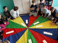 a group of children sitting around a colorful kite with writing on the bottom and sides