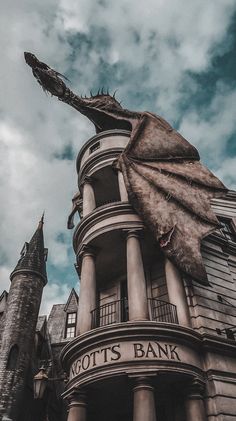 a giant dragon statue on top of a building next to a tall tower with a sign that says not's bank