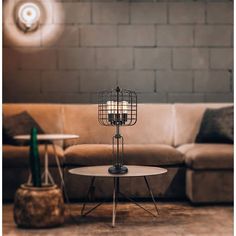 a living room with a couch, table and lamp on the floor in front of a brick wall