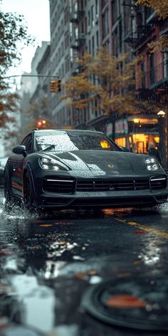 a black sports car driving down a street in the rain