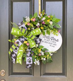 a welcome wreath on the front door of a house with dog paws and flowers