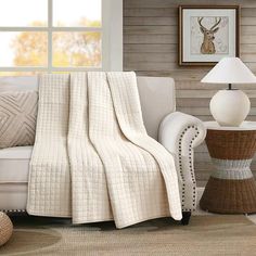 a living room with a couch, chair and table covered in a white quilted blanket
