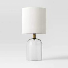 a clear glass table lamp with a white shade