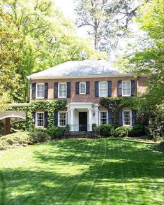 a large brick house surrounded by lush green grass and trees in front of the house