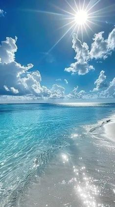 the sun shines brightly over an ocean beach with clear blue water and white sand