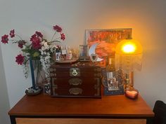 a wooden table topped with boxes and vases filled with flowers next to a lamp