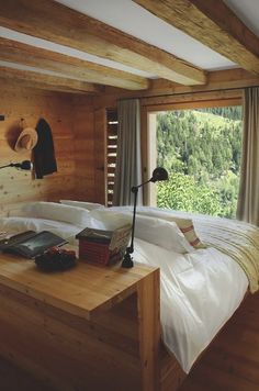 a bed in a bedroom next to a window with wooden walls and flooring on both sides