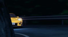 a yellow sports car driving down the road at night