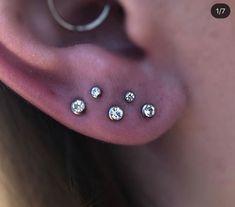 a woman's ear with three piercings on it