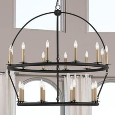 a chandelier with candles hanging from it's center and windows in the background