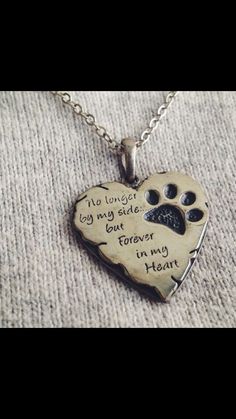 a heart shaped pendant with a dog paw on it's side and the words, no longer by my side but forever in my heart