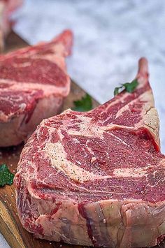 two raw meats are sitting on a cutting board