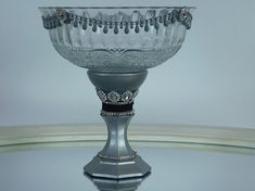 a glass bowl sitting on top of a table next to a white wall and floor