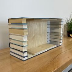 a stack of books sitting on top of a wooden table next to a potted plant