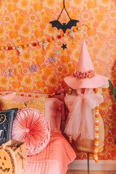 a bedroom decorated in pink and orange with halloween decorations on the wall, bedding and pillows